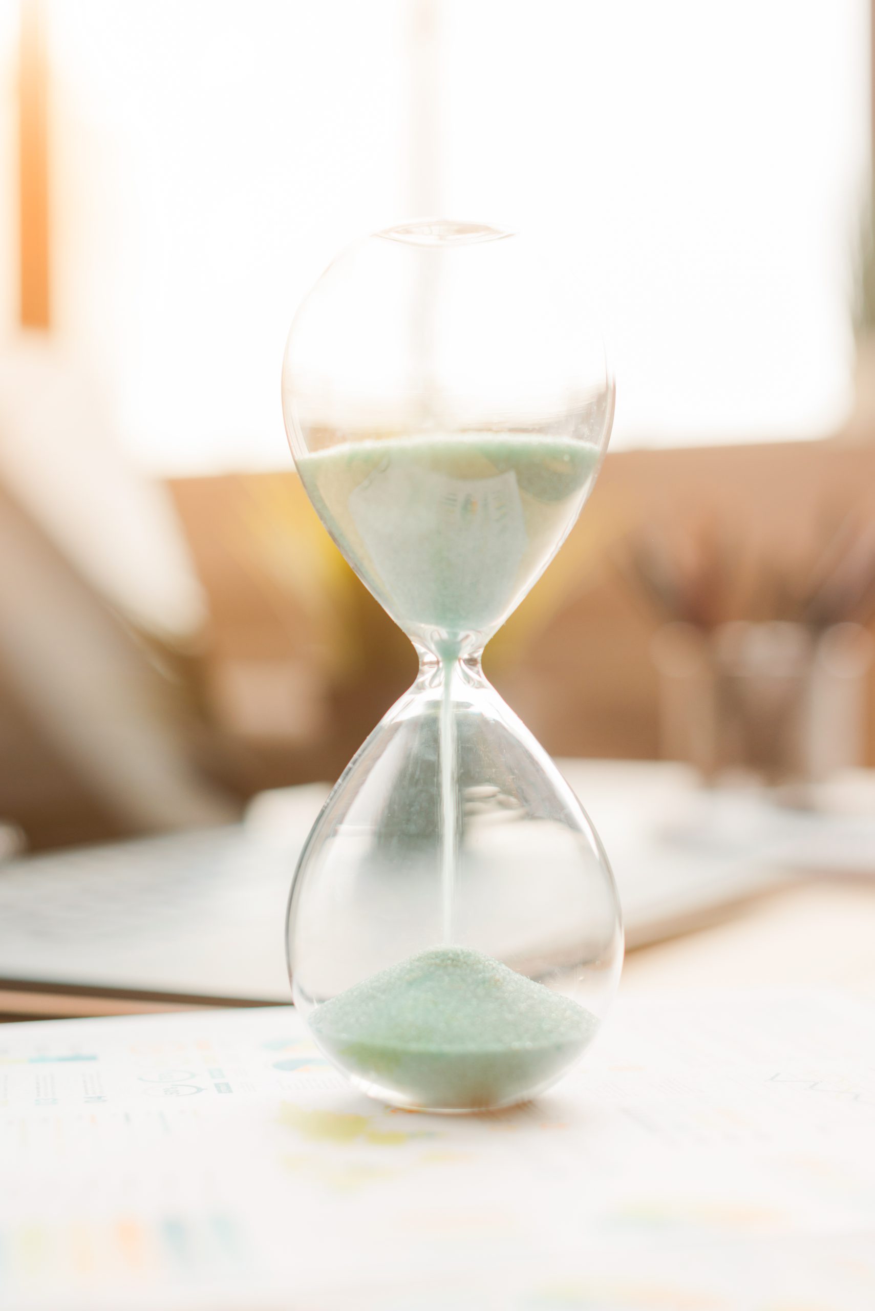 Nahaufnahme einer Sanduhr mit grünem Sand – Symbol für kindliche Zeitwahrnehmung und Übergänge im Alltag. Montessori im Alltag
